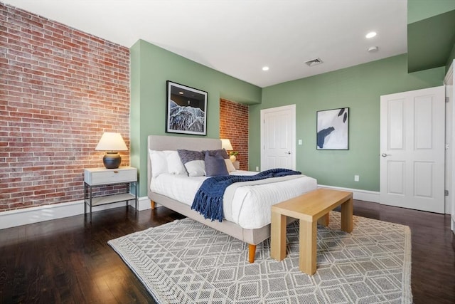 bedroom with brick wall and dark hardwood / wood-style floors