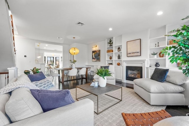 living room featuring built in shelves and light hardwood / wood-style floors