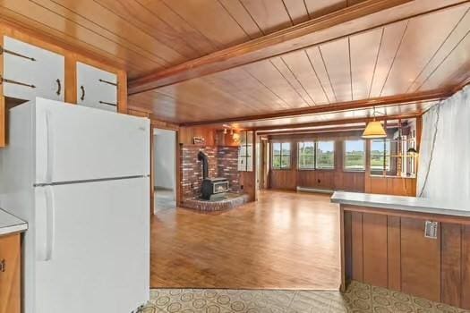 10 Sandpiper Ter, Wareham, MA 02571 - kitchen featuring freestanding refrigerator, wooden ceiling, a wood stove, wooden walls, and wood finished floors