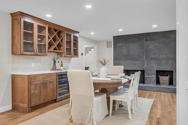 dining area with wine cooler, indoor bar, and light wood-type flooring