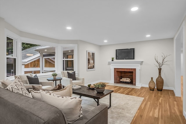 living room with light hardwood / wood-style flooring and a brick fireplace