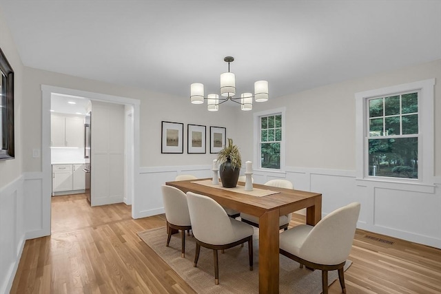 dining area with a notable chandelier and light hardwood / wood-style flooring