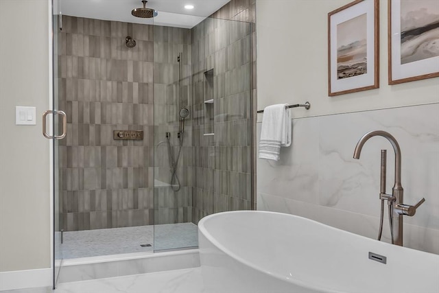 bathroom featuring plus walk in shower, sink, and tile walls