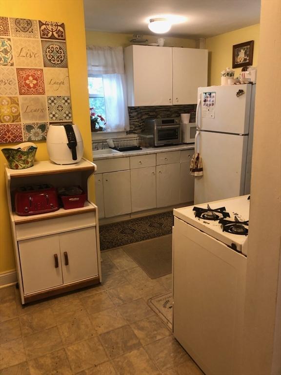 81 Bellevue Ave, Haverhill, MA 01832 - kitchen with white appliances, decorative backsplash, white cabinets, and light countertops