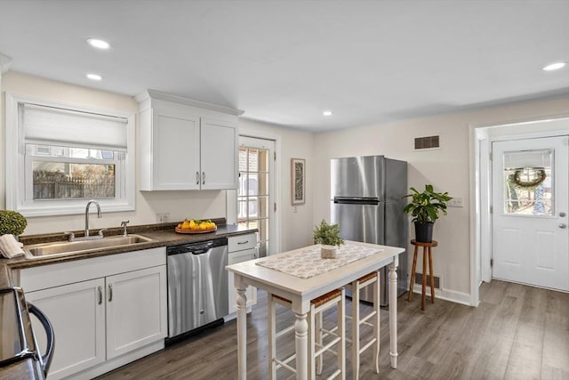 kitchen with dark countertops, visible vents, dark wood-type flooring, appliances with stainless steel finishes, and a sink