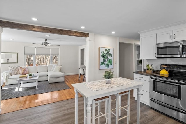 kitchen with recessed lighting, stainless steel appliances, wood finished floors, and white cabinetry