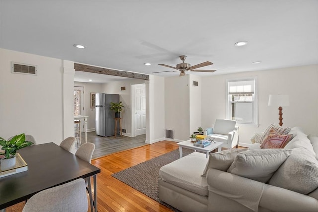 living room with recessed lighting, visible vents, and light wood finished floors