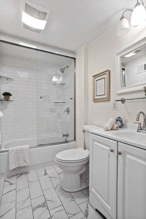 bathroom featuring visible vents, combined bath / shower with glass door, a textured ceiling, toilet, and marble finish floor