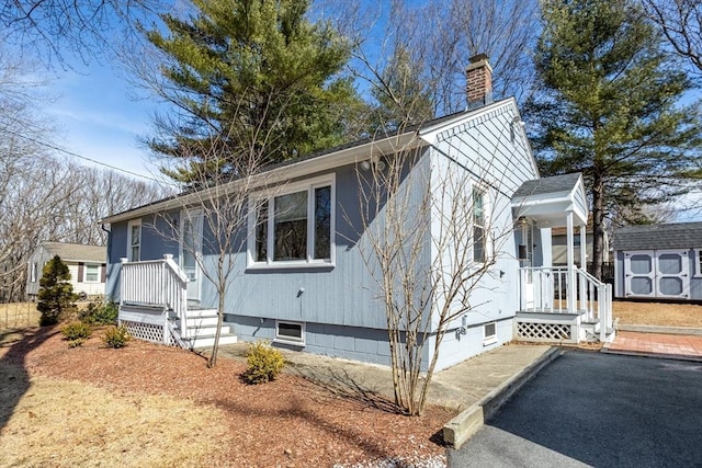 view of front of home featuring an outbuilding, a chimney, and a storage unit