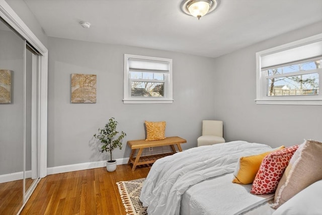 bedroom with wood finished floors, a closet, and baseboards