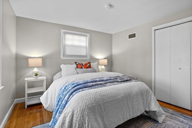 bedroom featuring visible vents, baseboards, a closet, and wood finished floors