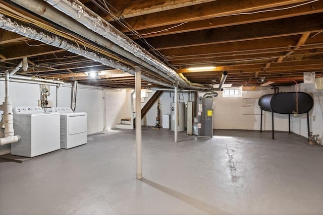 basement featuring stairway, heating unit, electric water heater, and washing machine and dryer