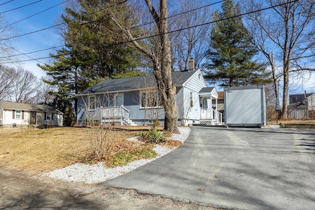 view of front facade featuring driveway and a chimney