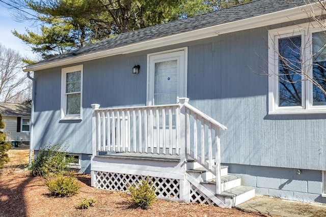 doorway to property with roof with shingles