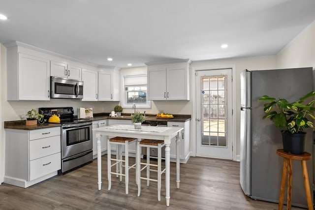 kitchen with white cabinetry, dark countertops, dark wood finished floors, and appliances with stainless steel finishes