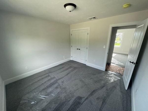 unfurnished bedroom featuring dark colored carpet and a closet