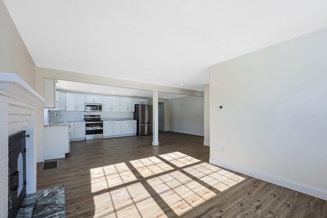 unfurnished living room featuring sink and dark hardwood / wood-style floors