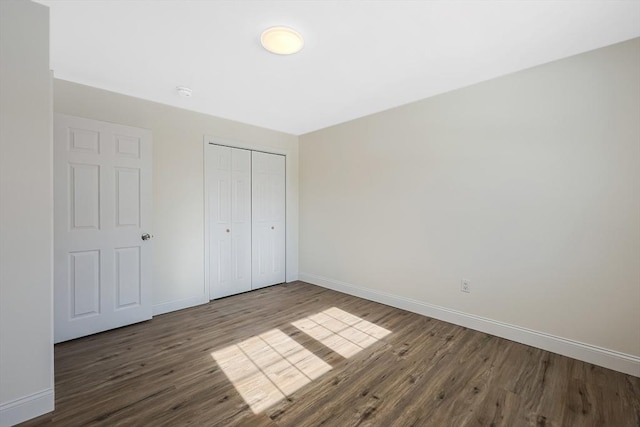 unfurnished bedroom with dark hardwood / wood-style flooring and a closet