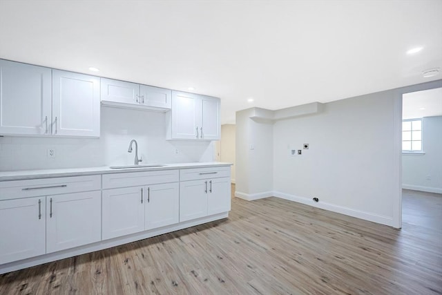 kitchen featuring white cabinetry, sink, and light wood-type flooring