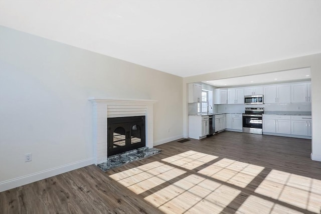 unfurnished living room with a brick fireplace, dark hardwood / wood-style floors, and sink