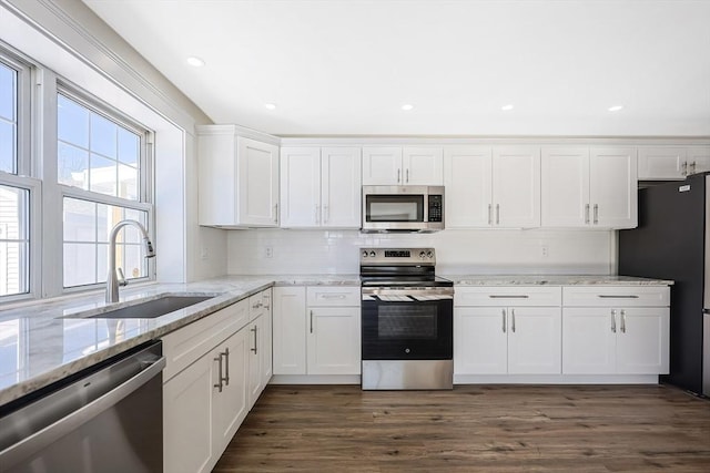 kitchen featuring sink, dark wood-type flooring, appliances with stainless steel finishes, white cabinetry, and light stone counters