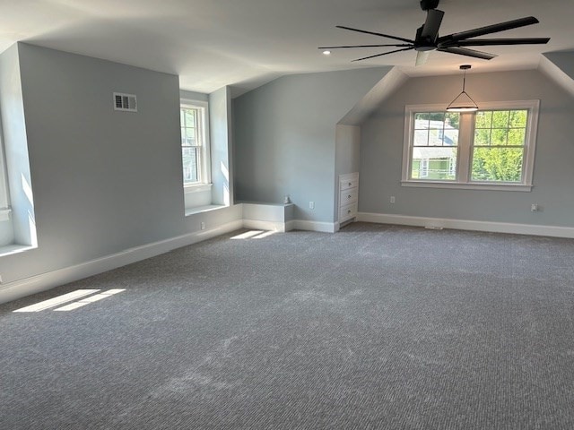 additional living space with ceiling fan, a healthy amount of sunlight, carpet flooring, and vaulted ceiling