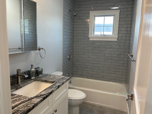 full bathroom featuring vanity, tiled shower / bath combo, and toilet