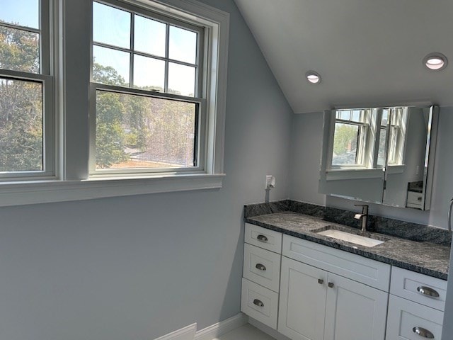 bathroom featuring vanity, lofted ceiling, and plenty of natural light