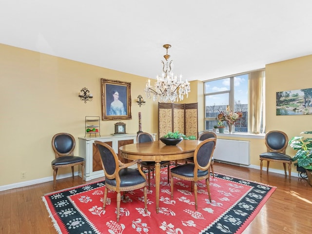 dining space with hardwood / wood-style floors, a chandelier, and radiator