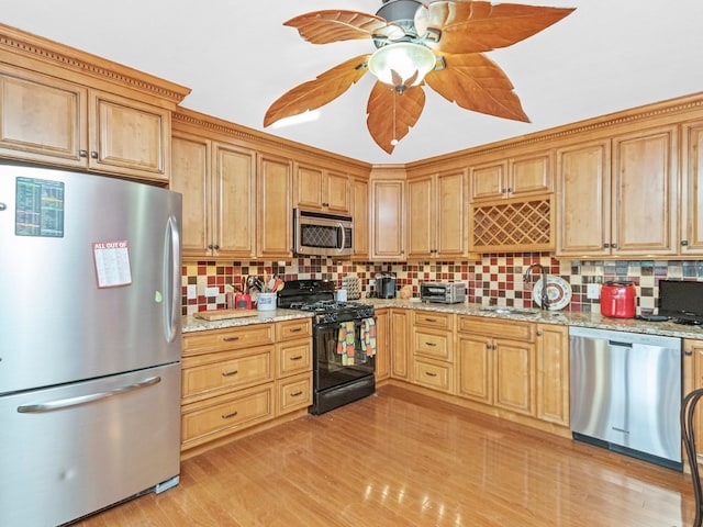 kitchen featuring backsplash, appliances with stainless steel finishes, light stone countertops, and light hardwood / wood-style floors