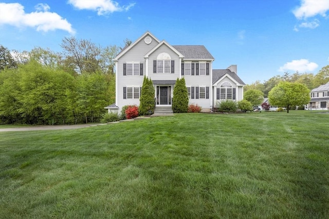 colonial inspired home featuring a front lawn and a chimney