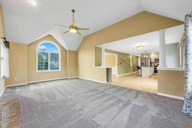 unfurnished living room featuring lofted ceiling, light colored carpet, ceiling fan, baseboards, and ornate columns