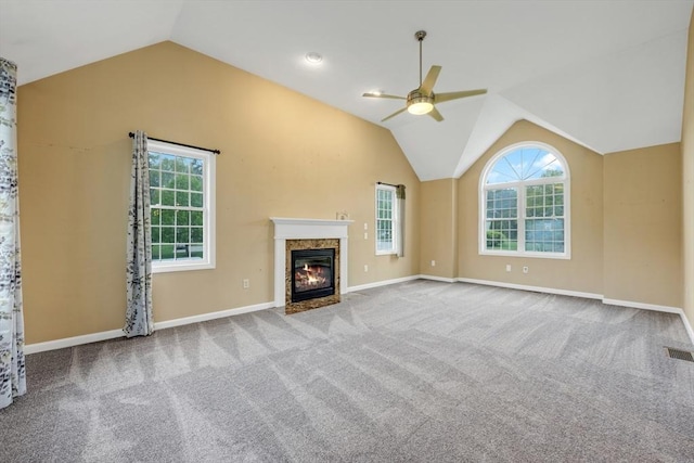 unfurnished living room with ceiling fan, lofted ceiling, plenty of natural light, carpet, and a fireplace