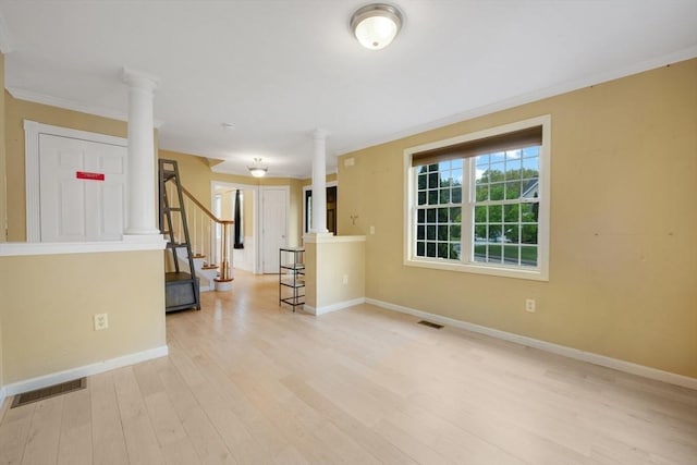 spare room with ornate columns, baseboards, light wood-style floors, and ornamental molding