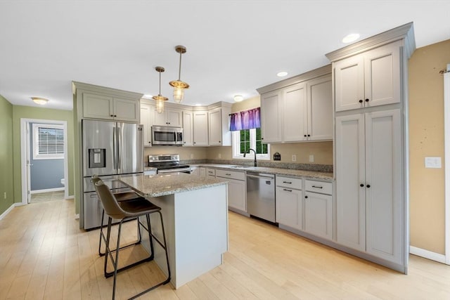 kitchen with appliances with stainless steel finishes, baseboards, light stone counters, light wood-style floors, and recessed lighting