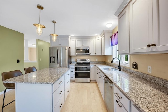 kitchen with appliances with stainless steel finishes, a sink, a breakfast bar, and light wood finished floors