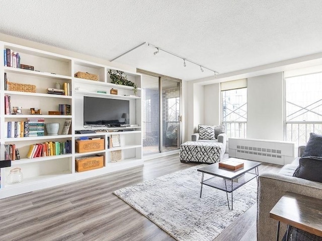 living area with track lighting, a textured ceiling, wood finished floors, and radiator