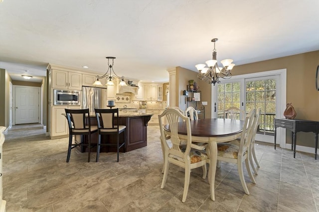 dining area with a chandelier, baseboards, and stone finish floor