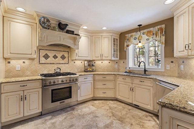 kitchen with appliances with stainless steel finishes, cream cabinetry, custom exhaust hood, and a sink