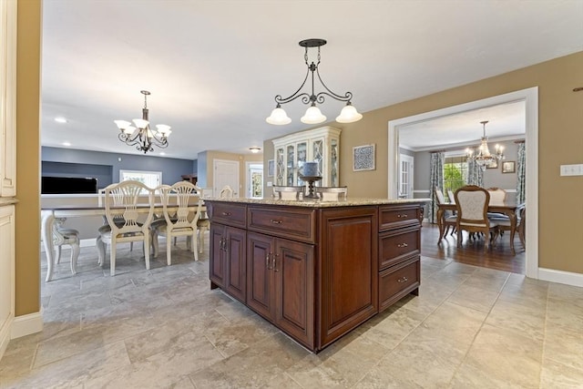 kitchen with pendant lighting, an inviting chandelier, light stone counters, and baseboards