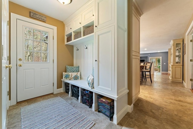 mudroom featuring stone finish flooring and baseboards