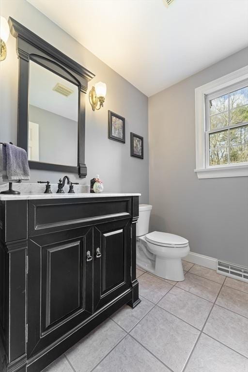 half bathroom with vanity, toilet, visible vents, baseboards, and tile patterned flooring
