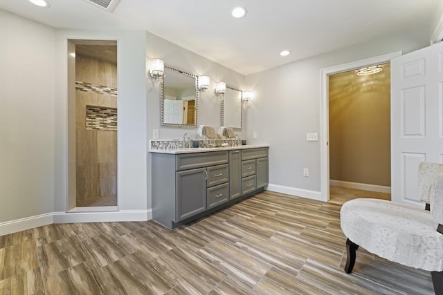 full bathroom with recessed lighting, tiled shower, vanity, and baseboards