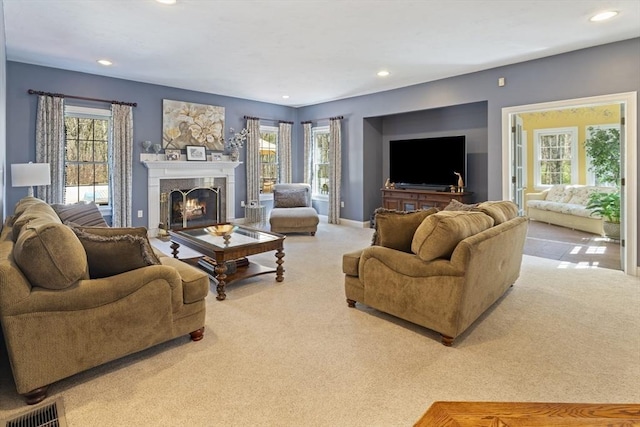 living area featuring a lit fireplace, recessed lighting, a wealth of natural light, and carpet