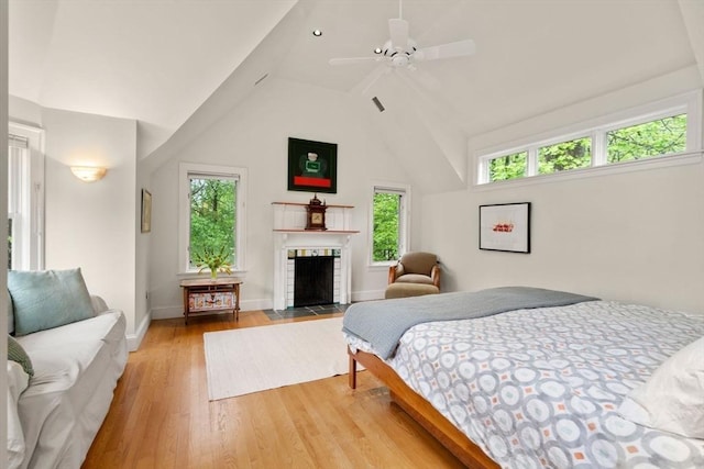 bedroom featuring light wood-style flooring, baseboards, vaulted ceiling, and a fireplace