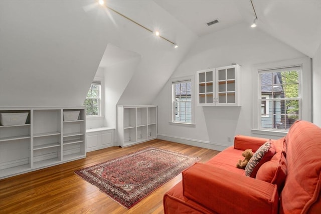 sitting room featuring track lighting, vaulted ceiling, healthy amount of natural light, and wood finished floors