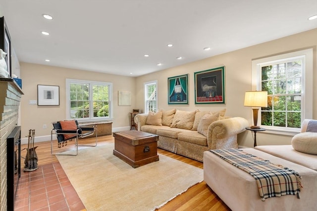 living area featuring a brick fireplace, recessed lighting, baseboards, and light wood-style floors