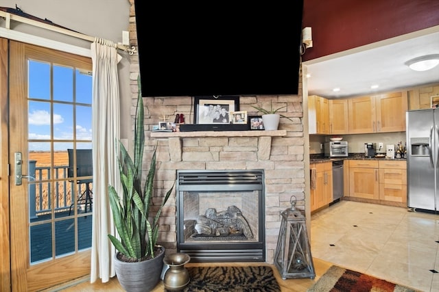 kitchen featuring a fireplace, light brown cabinets, light tile patterned flooring, and stainless steel refrigerator with ice dispenser