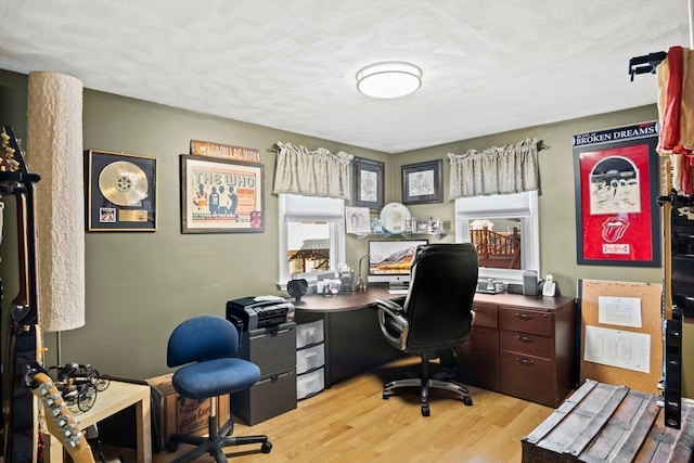 home office with a textured ceiling and light hardwood / wood-style flooring