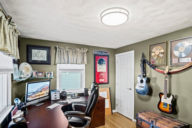 home office featuring plenty of natural light, light hardwood / wood-style floors, and a textured ceiling